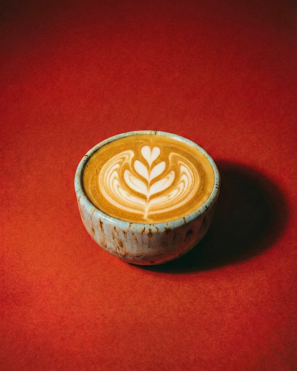 A flat white made with clayman coffee's organic ember coffee beans, using the clayman coffee blue ceramic cup. 