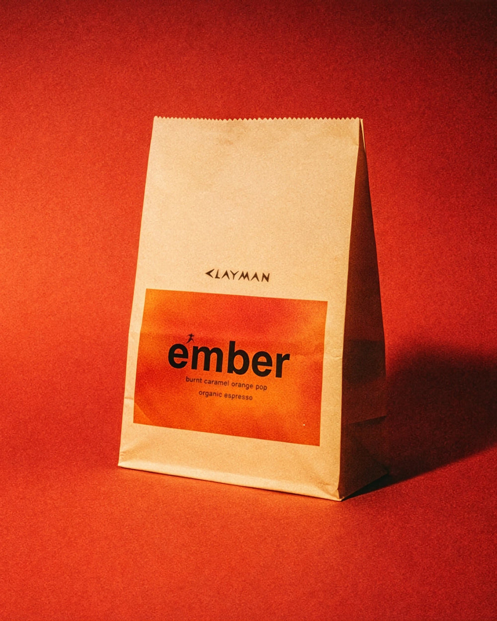 clayman coffee organic coffee beans on red background; organic ember blend in kraft paper coffee beans bag. 